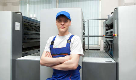 Young man in cap working in print factoryの写真素材