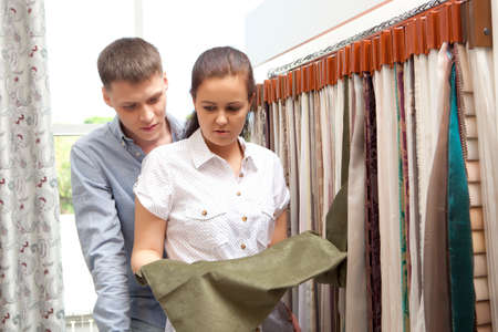 Couple select colorful curtain samples hanging  in home decoration storeの写真素材