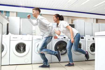 Happy family couple buying new washing machine in storeの写真素材