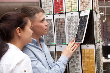Young happy family couple having fun in store choosing for buying ceramic mosaic looking at design imageの写真素材