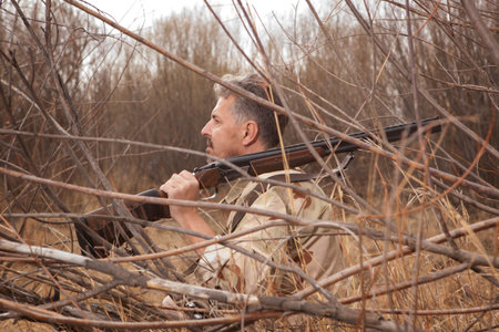 Hunter in camouflage clothes ready to hunt with hunting rifle