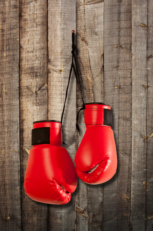 Pair of red boxing gloves hanging on wooden wall