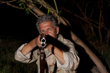Night poacher. Man in camouflage clothes ready to hunt with hunting rifle