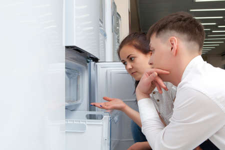 Happy family couple looking at large fridges in the storeの写真素材