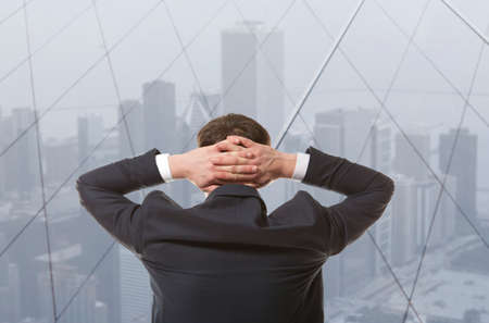 Young businessman looking out of a windowの写真素材