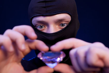 Thief. Man in black mask with a big emerald over dark blue background
