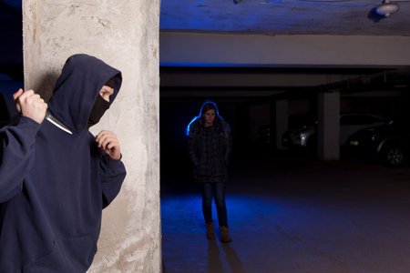Criminal with knife waiting for a woman. Robbery concept