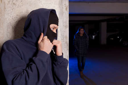 Criminal wearing a mask waiting for a woman. Robbery conceptの写真素材