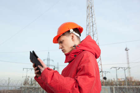 Engineer at electrical substation using a tablet computer. Electrical power industryの写真素材