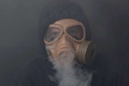 A man in a gas mask in the smoke. Black backgroundの写真素材