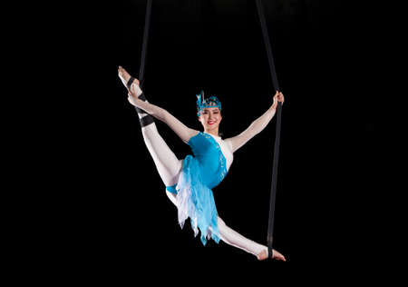 Young woman circus air gymnast. On black background の写真素材