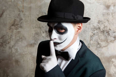 Scary evil clown wearing a bowler hat on wall backgroundの写真素材