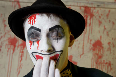 Scary evil clown wearing a bowler hat on wall backgroundの写真素材