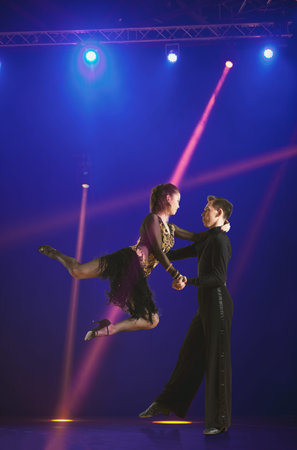 Beautiful couple ballroom dancing on illumination background