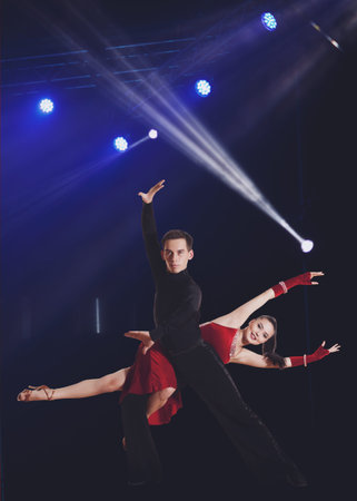 Beautiful couple ballroom dancing on illumination background