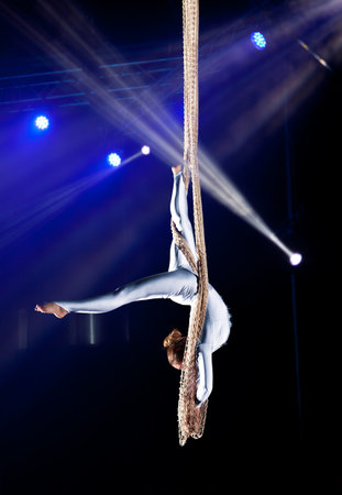Young woman circus air gymnast. On illumination background