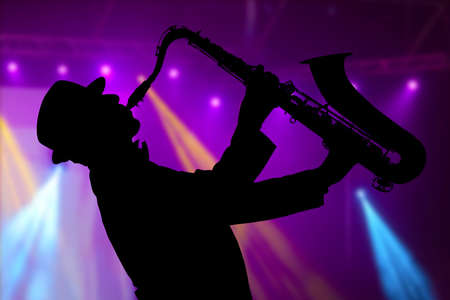 Saxophonist. Man playing on saxophone against the background of beautiful lightの写真素材