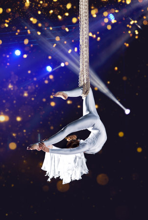 Young woman circus air gymnast. On illumination background
