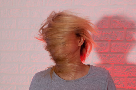 Portrait of blonde girl with fluttering hair. On wall background