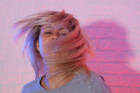 Portrait of blonde girl with fluttering hair. On wall backgroundの写真素材