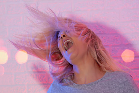 Portrait of blonde girl with fluttering hair. On wall background