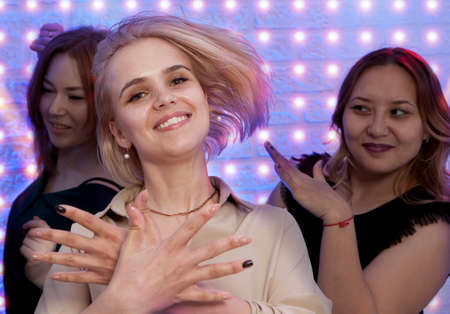 Blonde woman looking at camera while dancing at nightclub among her friendsの写真素材