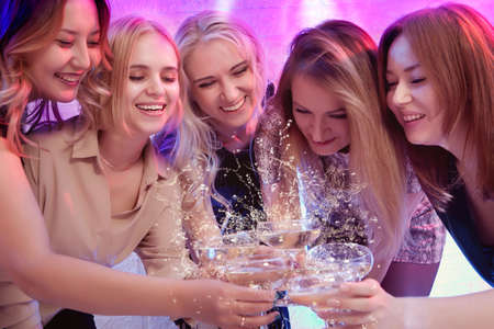 Group of partying girls clinking flutes with sparkling wineの写真素材
