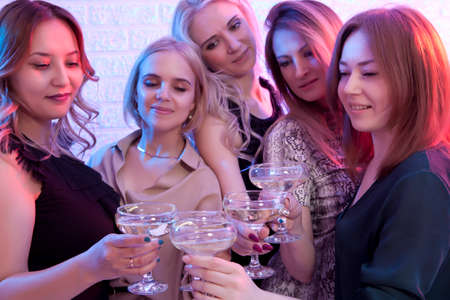 Group of partying girls clinking flutes with sparkling wine. Focus on glassesの写真素材