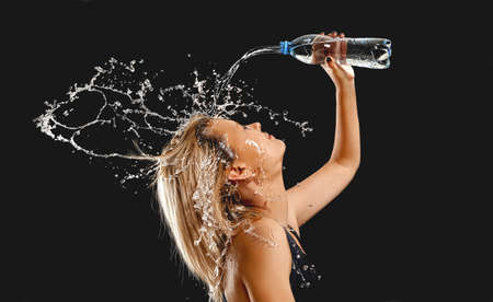 Splashes of water on the face of woman - black backgroundの写真素材