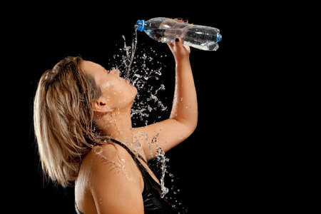 Splashes of water on the face of woman - black backgroundの写真素材