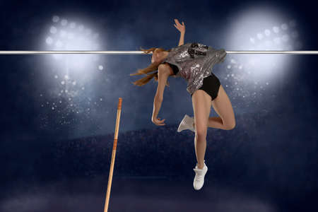 Competition pole vault jumper female on stadium at night backgroundの写真素材