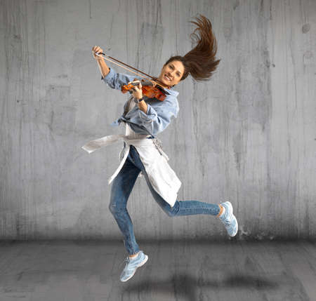 Woman playing violin on grey backgroundの写真素材