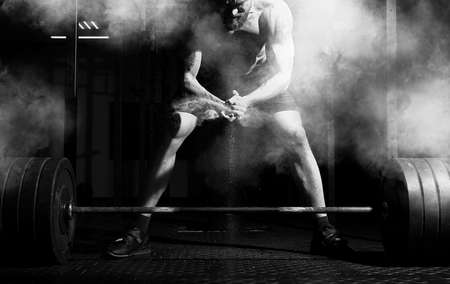 Weightlifter clapping hands and preparing for workout at a gym. Focus on dustの写真素材