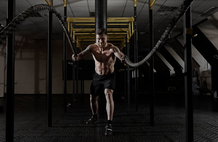 Man working out with battle ropes at gym