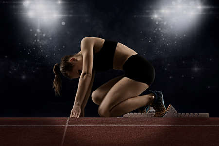 Woman sprinter leaving starting blocks on the athletic track. Exploding startの写真素材