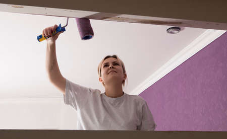 Home improvement - handywoman painting wall with rollerの写真素材