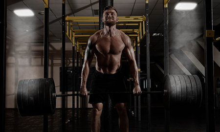 Deadlift. Portrait of a muscular man workout with barbell at gym