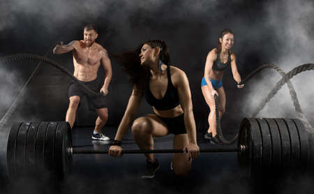 Woman and men working out with battle ropes at gymの写真素材