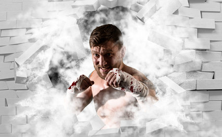 Muscular kick-box or muay thai fighter punching in smoke