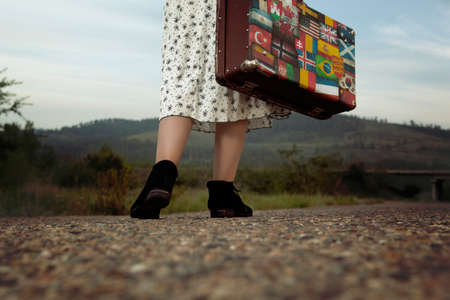 Woman with vintage travel suitcase at old roadの写真素材