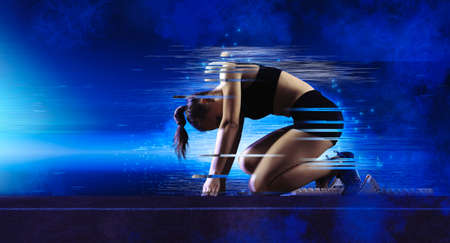 Woman sprinter leaving starting blocks on the athletic trackの写真素材