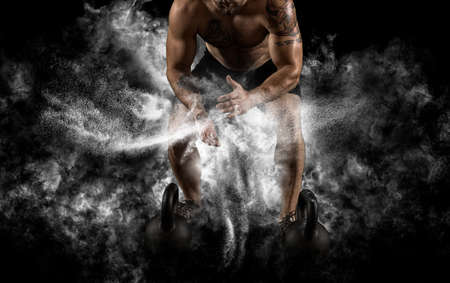Muscular man clapping hands and preparing for workout at a gym. Focus on dustの写真素材