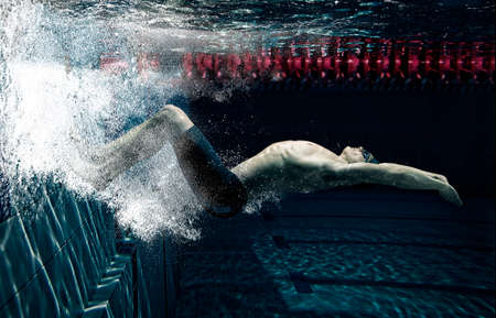 Professional male swimmer in action inside swimming pool. View underwaterの写真素材