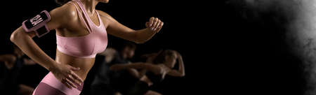 Sporty young woman running on black backgroundの写真素材
