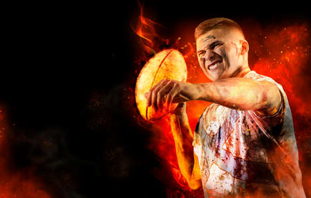 Man rugby player holds ball on fire background. Sports banner. Concept of sport, movement, energy, dynamic, healthy lifestyleの写真素材