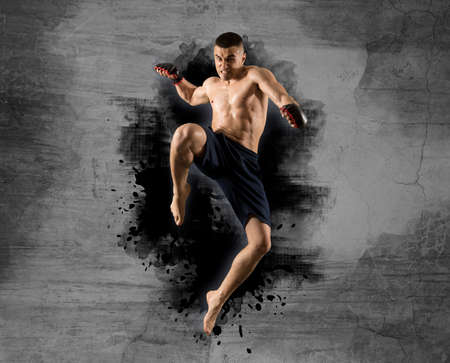 MMA male fighter jumping with a knee kick. Isolated on wall backgroundの写真素材