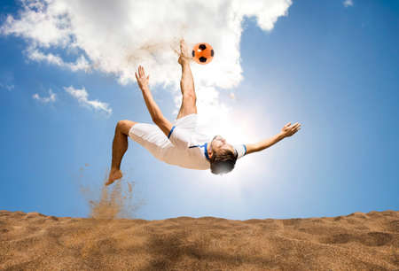 The man footballers are desperately playing beach soccer on sand on a sunny day. Man doing kick on beach with soccer ballの写真素材
