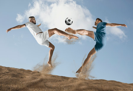 Two men footballers are desperately playing beach soccer on sand on a sunny day. Man doing kick on beach with soccer ballの写真素材