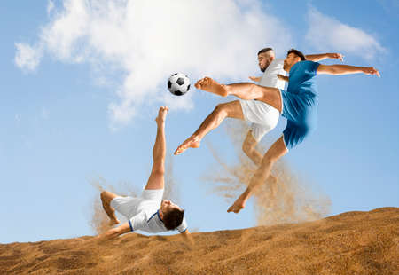 Three men footballers playing beach soccer on sand on a sunny day. Two image of the same model. Mixed mediaの写真素材