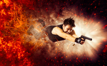 Excited man holding gun. movie concept. fire backgroundの写真素材